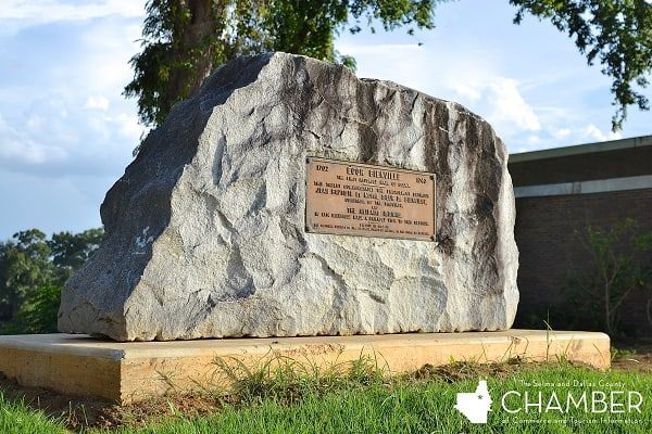 A large rock with a plaque on it in front of a building