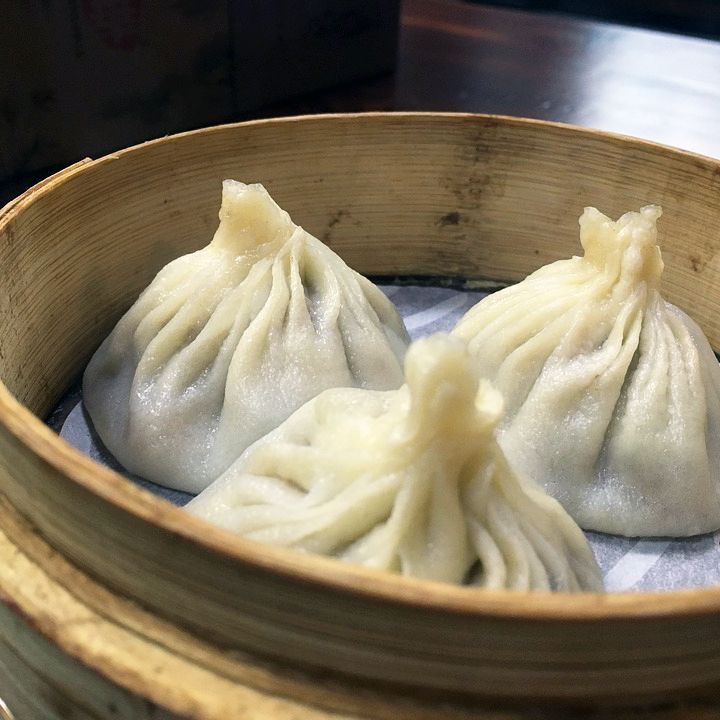 Three dumplings in a bamboo steamer on a table