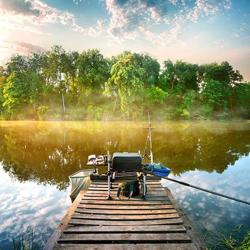 A boat is docked on a wooden dock next to a lake.