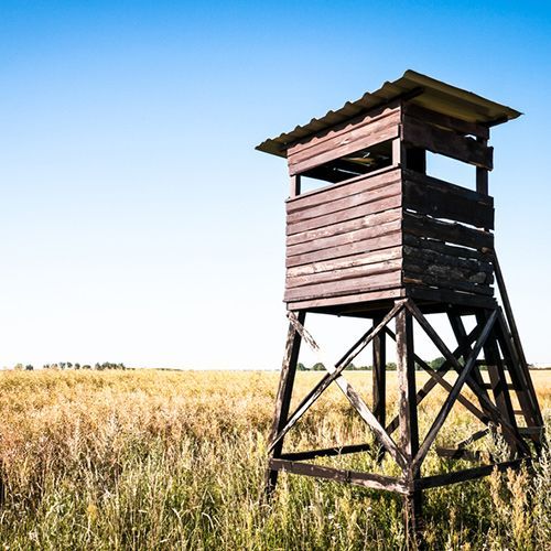 A wooden tower is sitting in the middle of a field.