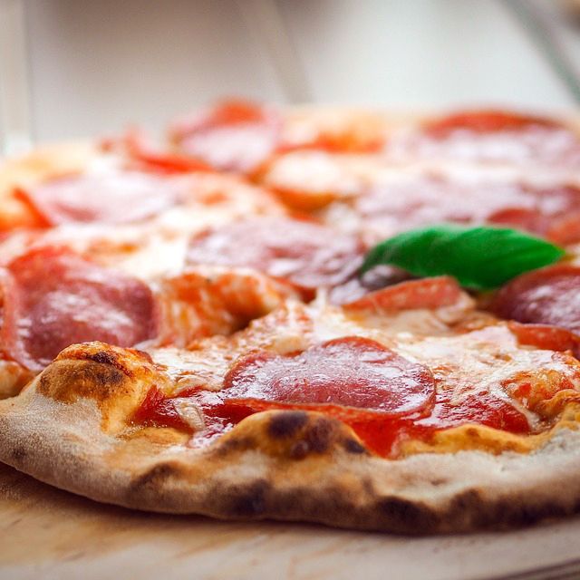 A pepperoni pizza is sitting on a wooden cutting board.
