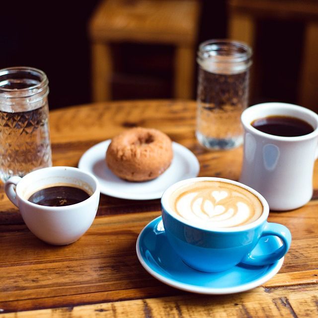 Three cups of coffee and a donut on a wooden table