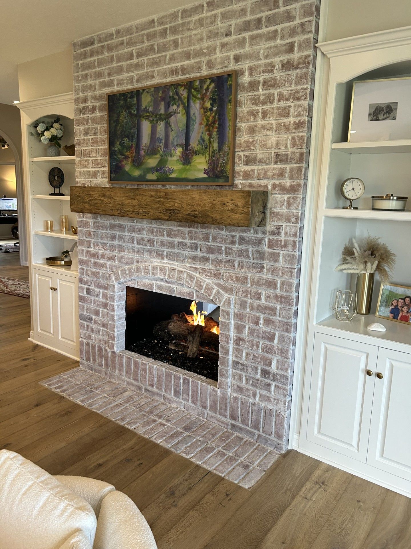 A living room with a fireplace and a painting on the mantle.