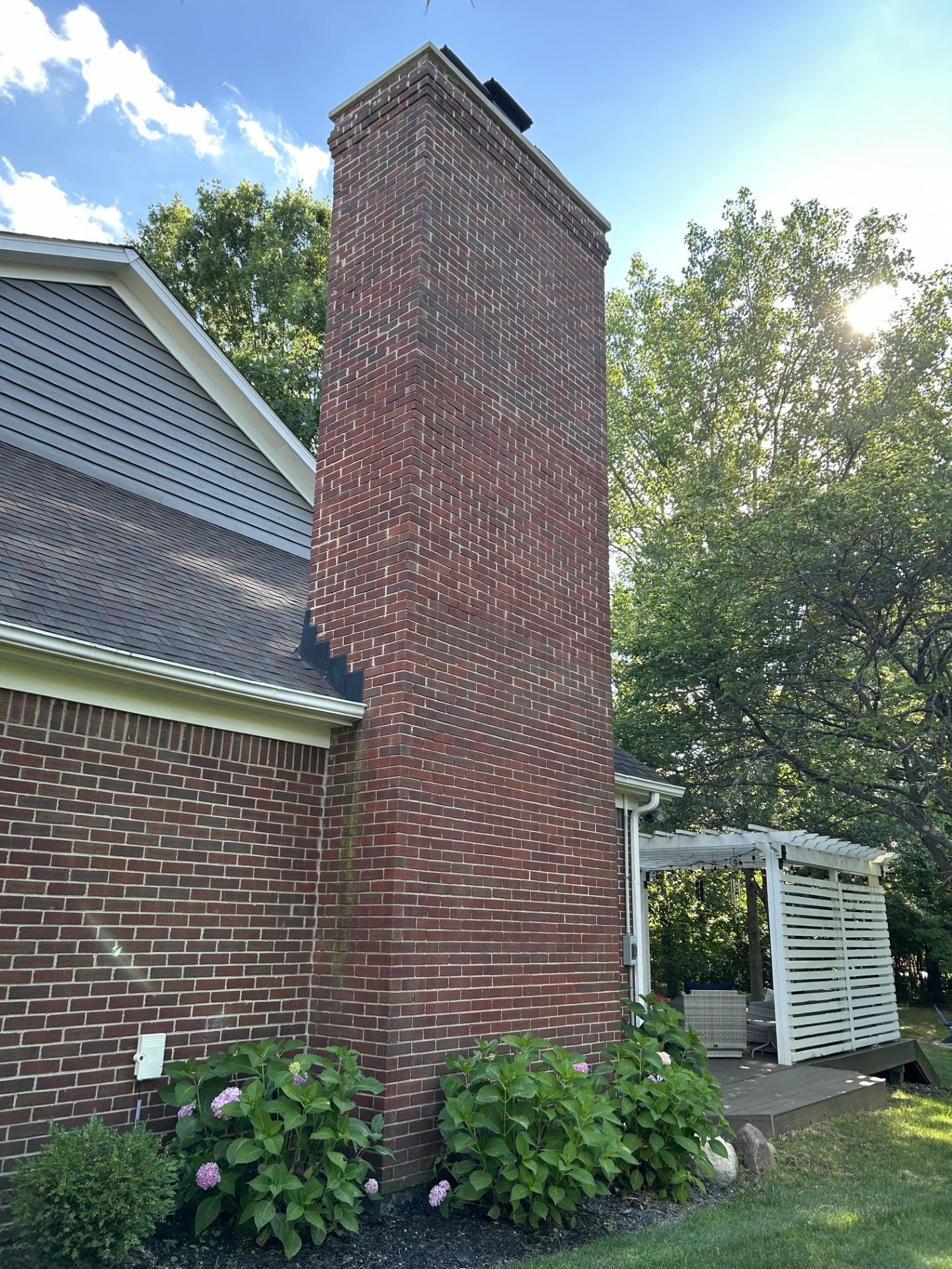 A large brick chimney on the side of a brick house.