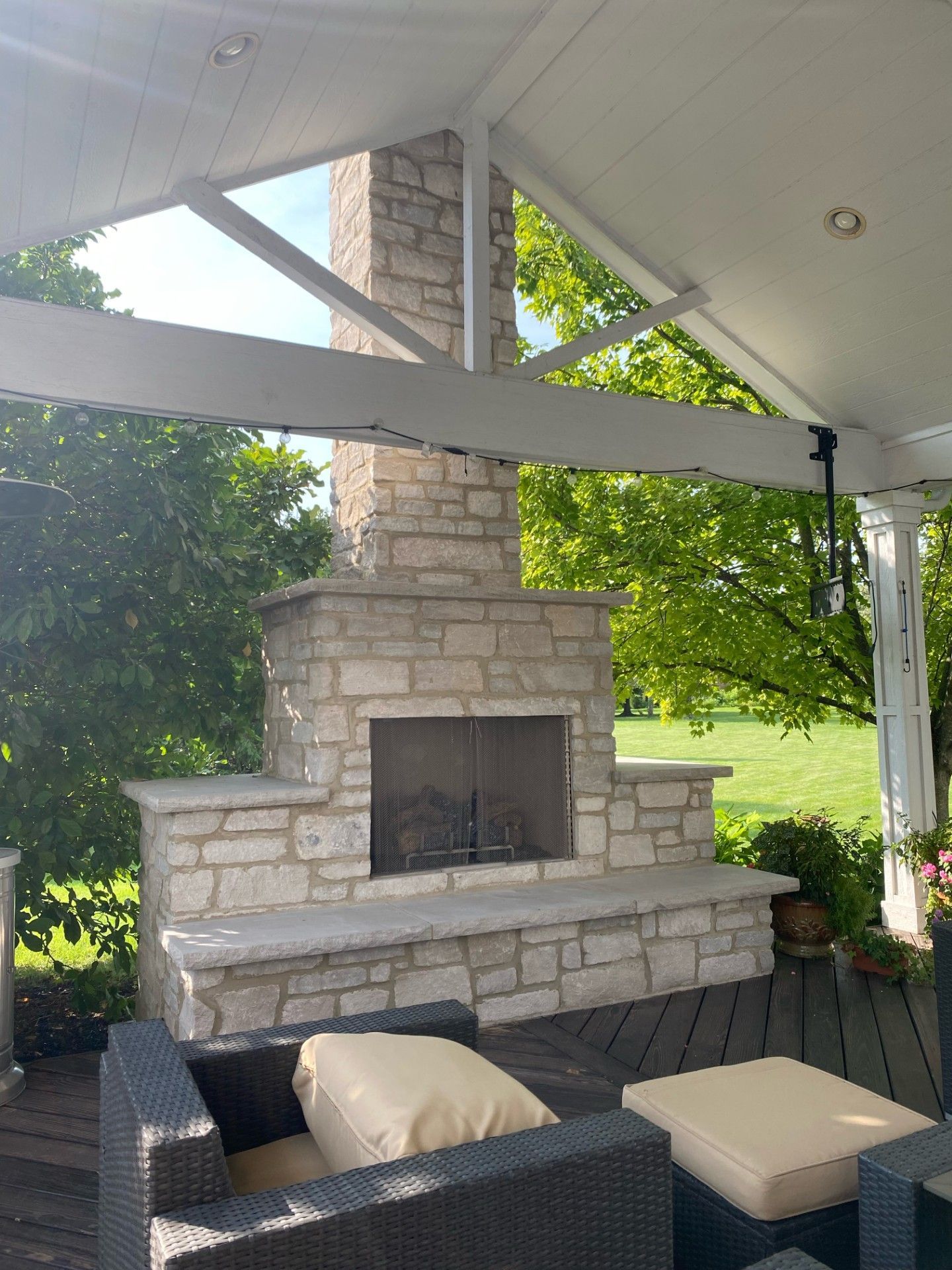 A patio with a fireplace and chairs under a canopy.