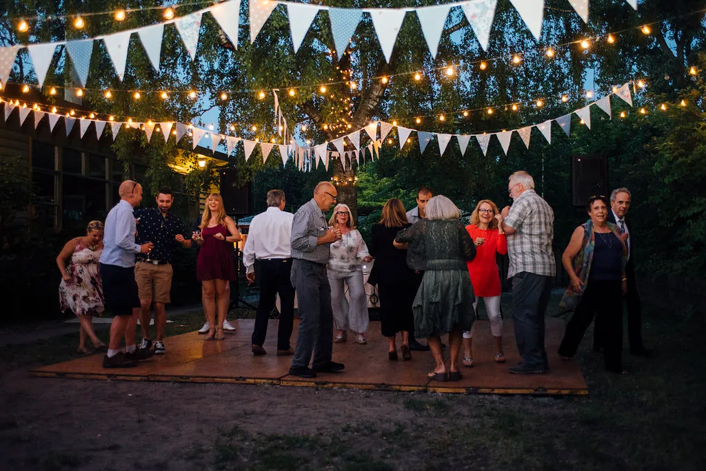 A group of people are dancing on a wooden dance floor.