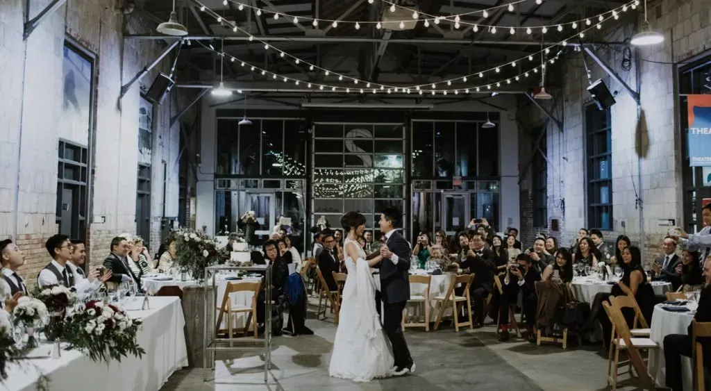 A bride and groom are dancing in front of a crowd at a wedding reception.