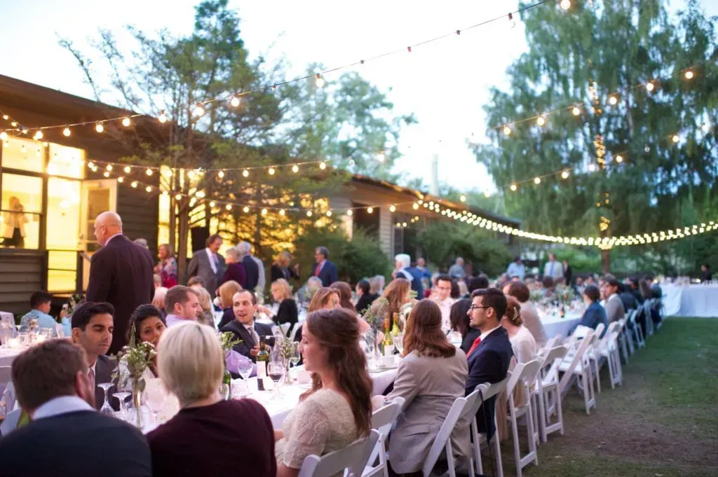 A group of people are sitting at long tables at a wedding reception.