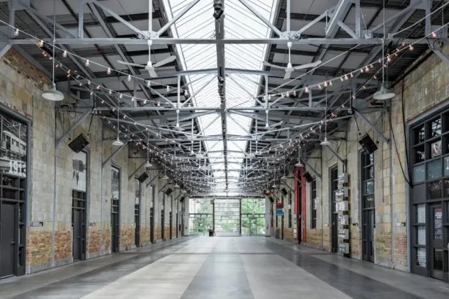 A large empty building with a lot of windows and lights hanging from the ceiling.