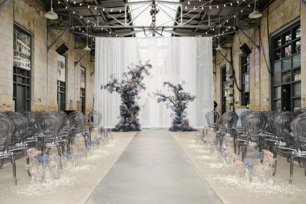 A rendering of a wedding ceremony in a warehouse with trees and chairs.