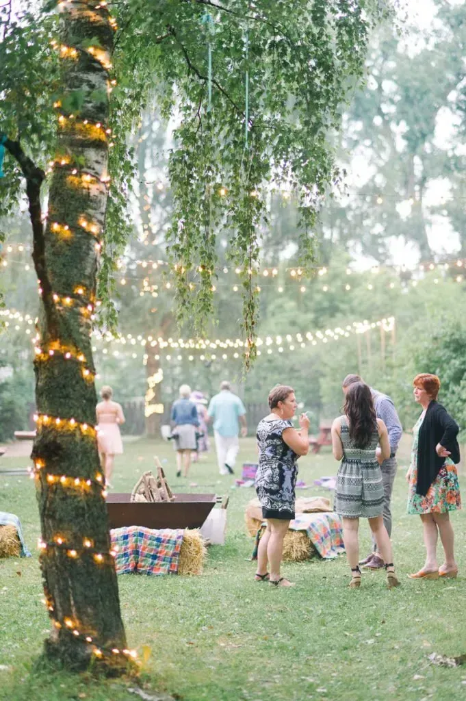 A group of people are standing around a tree with lights on it.