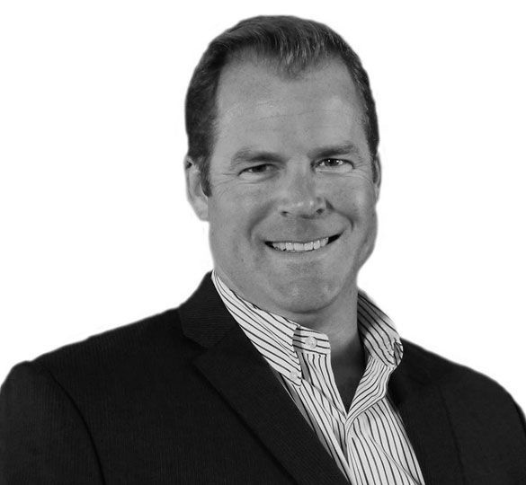 Man in suit jacket smiles, looking towards camera. Light and dark striped collared shirt underneath.