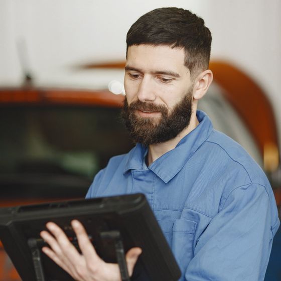 A man with a beard is using a computer in a garage.