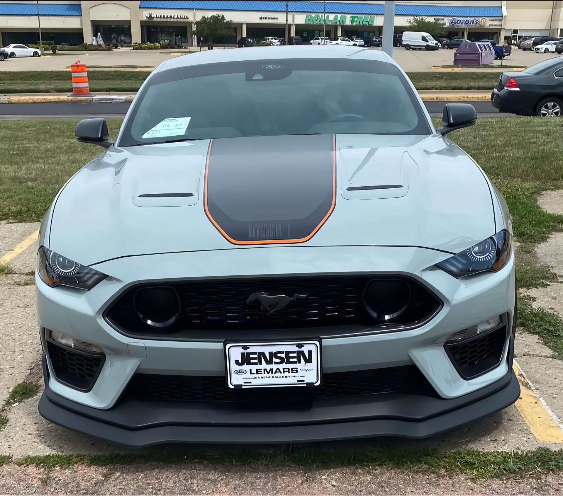 Front view of a gray sports car with black hood stripe parked in a lot