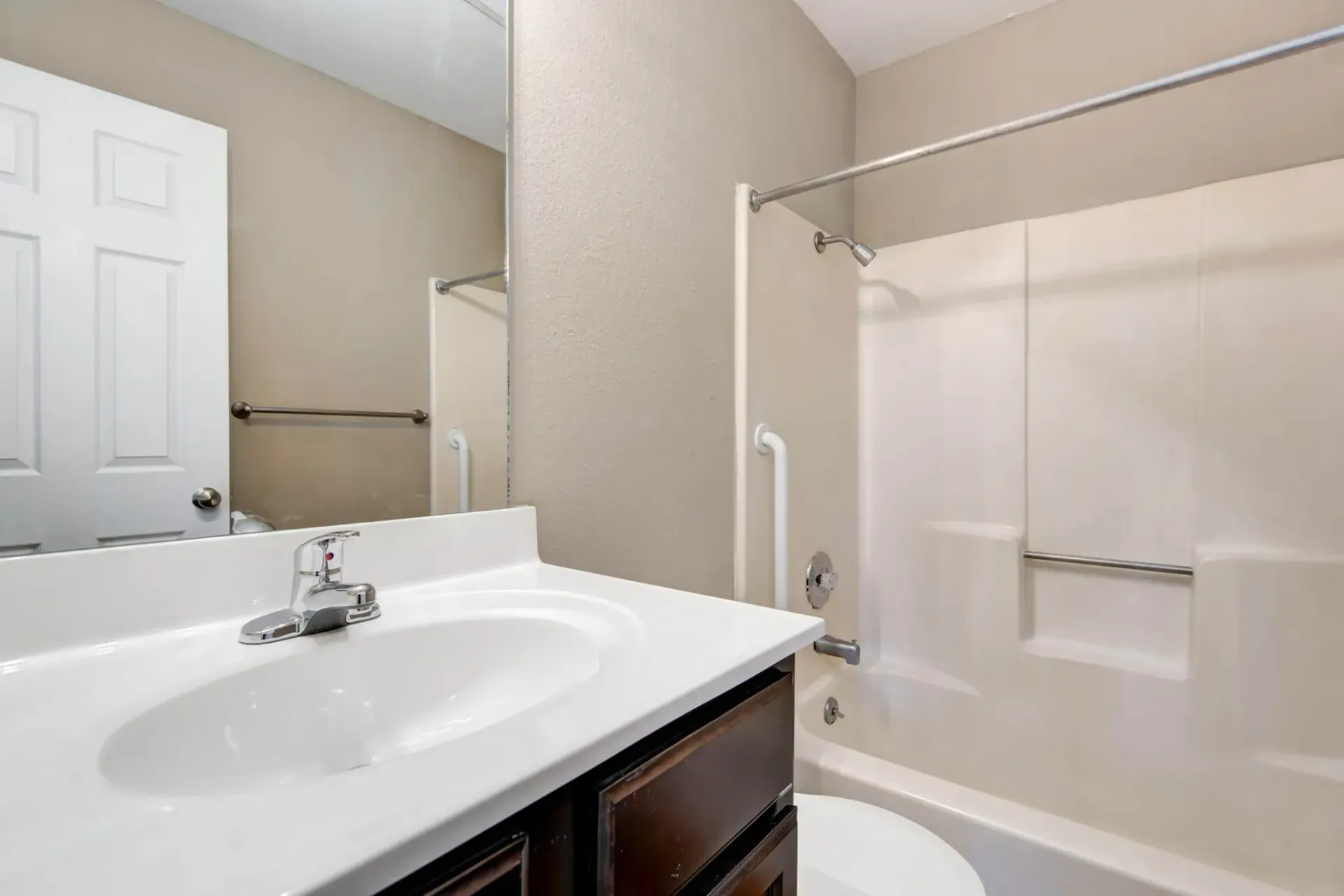 Photo of a bathroom with a wide mirror/sink and a bathtub/shower combo