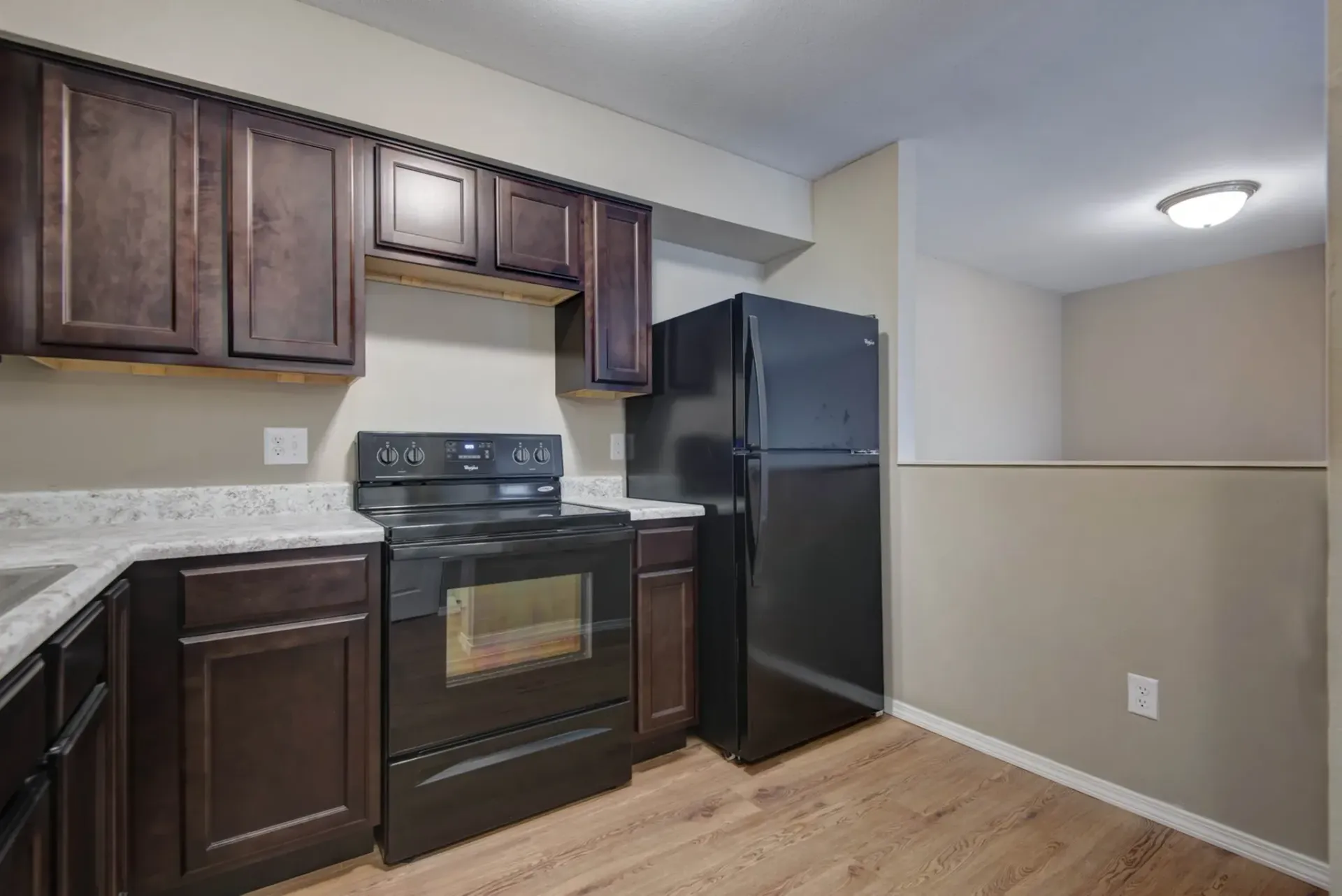 Photo of a refrigerator and a stove in an L-shaped kitchen