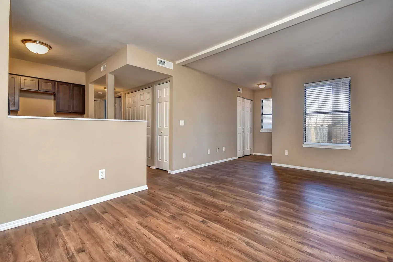 Photo of a living room area, with the kitchen in the background