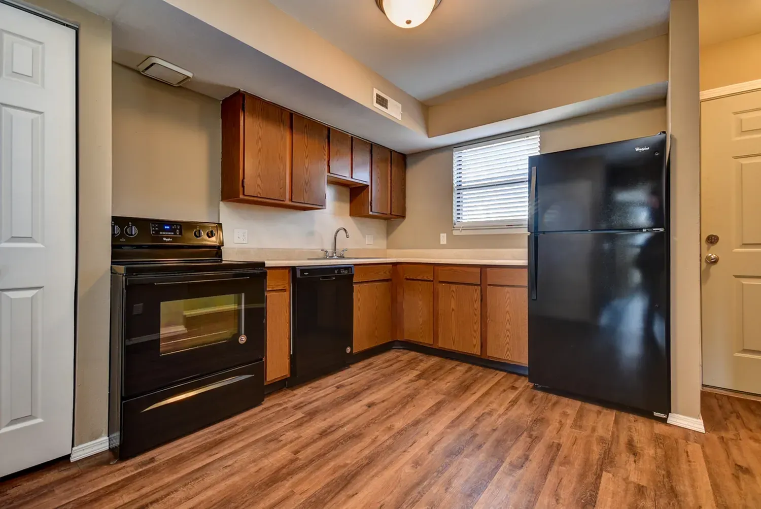 Photo of an L-shaped kitchen with a dishwasher, stove and a refrigerator