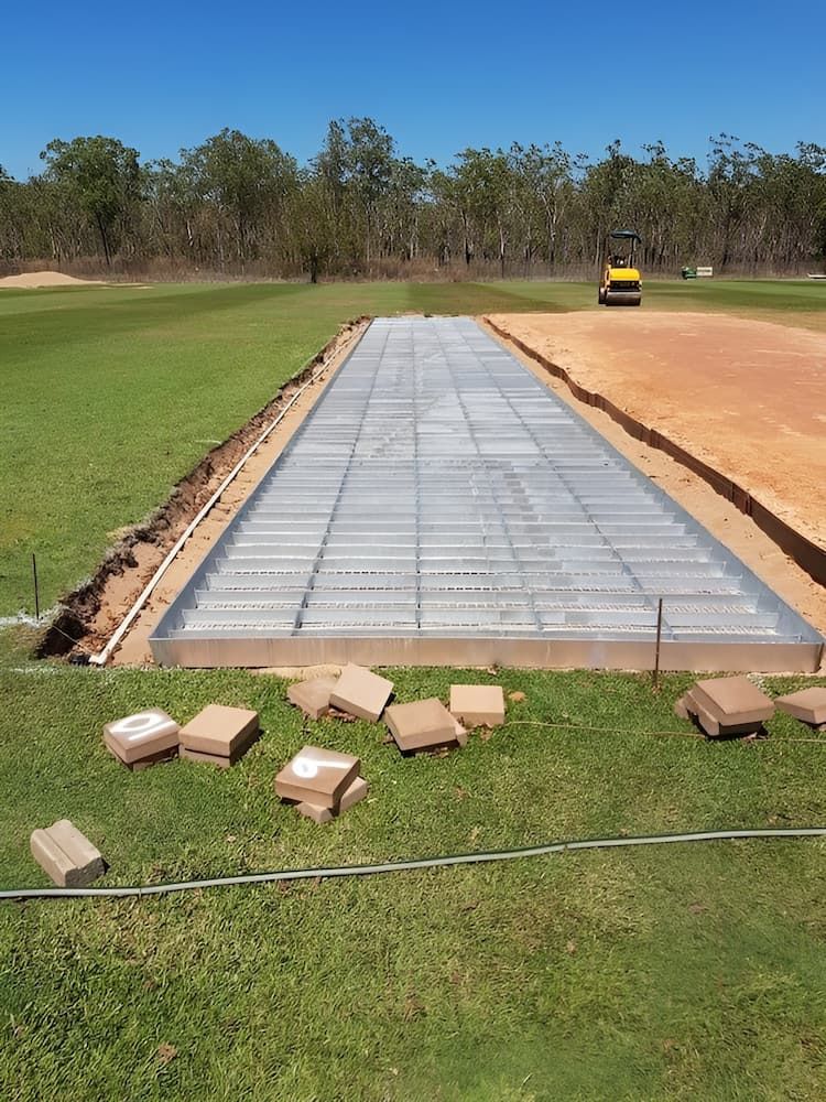 A Concrete Road Is Being Built In The Middle Of A Grassy Field — Jakes Steel & Welding in East Arm, NT