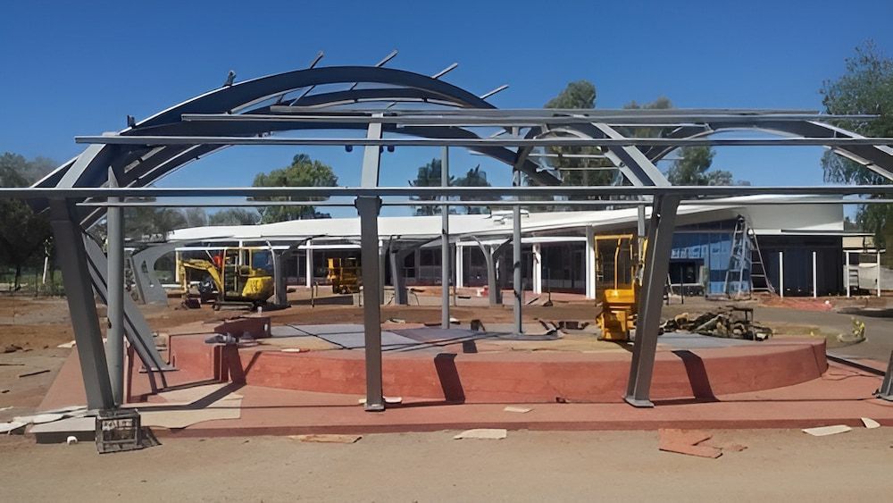 A Large Metal Structure Is Being Built In Front Of A Building Under Construction — Jakes Steel & Welding in East Arm, NT