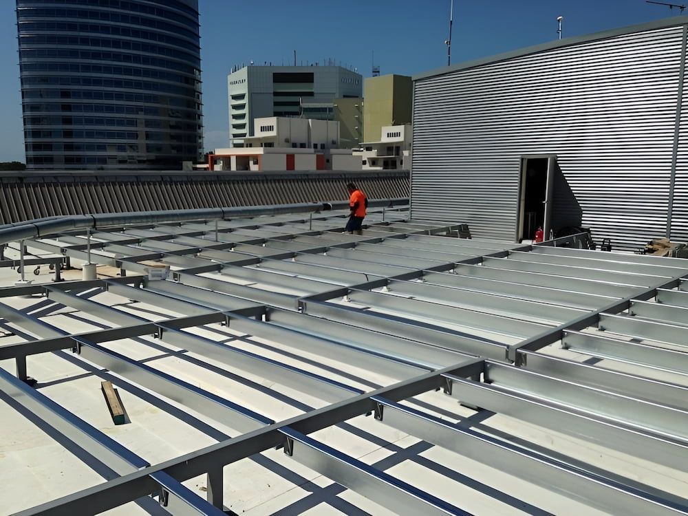 A Man Is Working On The Roof Of A Building — Jakes Steel & Welding in East Arm, NT