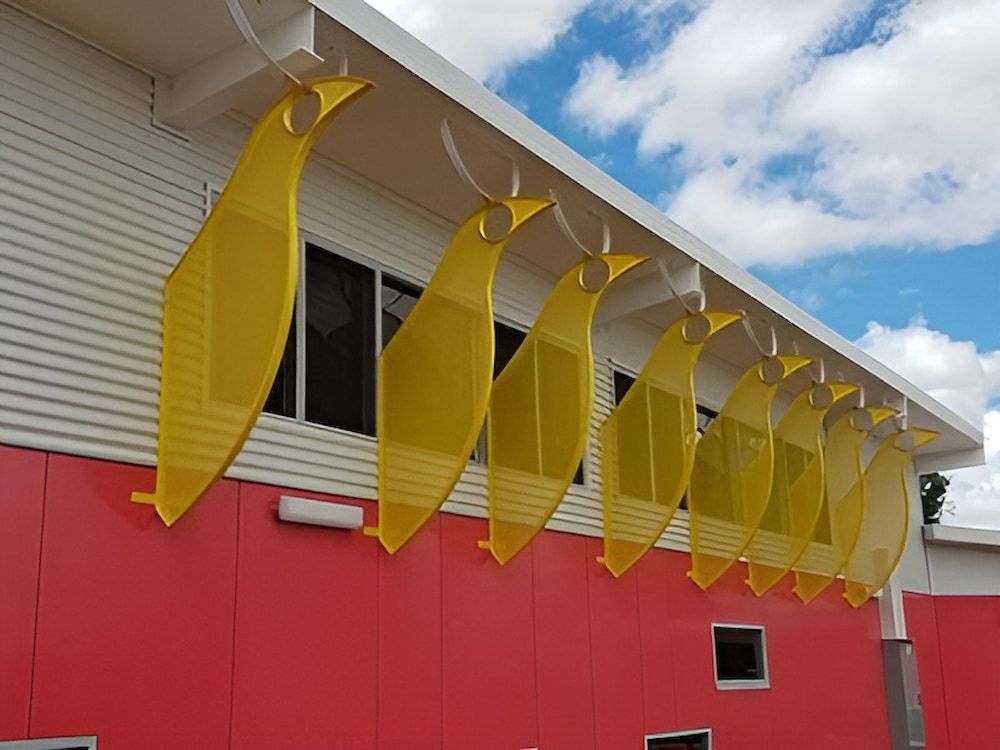 A Red Building With Yellow Birds Hanging From The Roof — Jakes Steel & Welding in East Arm, NT