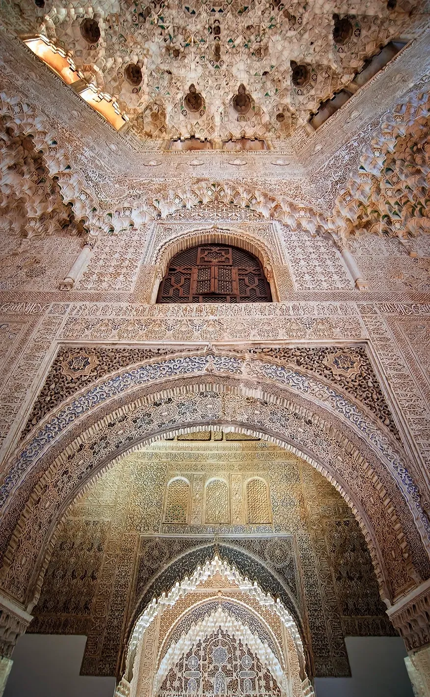 Elaborate, carved stone arches and ceiling of an ornate building interior.