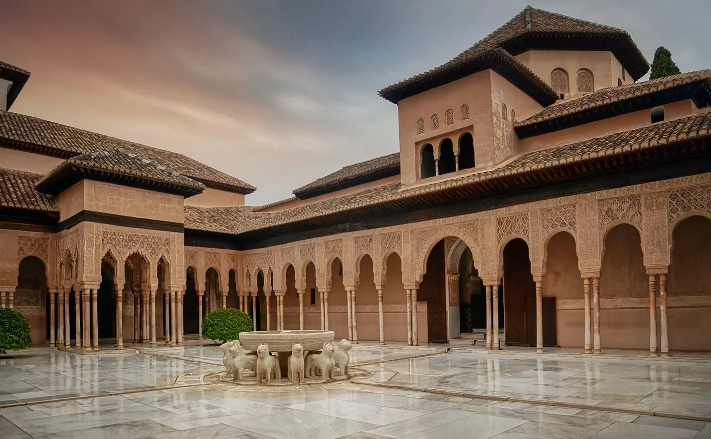 Courtyard of the Alhambra palace, Granada. Arches, columns, ornate carvings, reflecting pool, beige and brown tones.