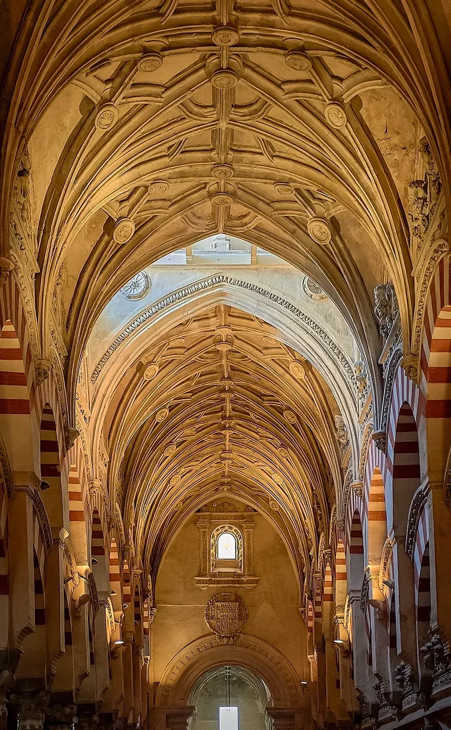 Ornate cathedral ceiling with archways and decorative carvings, beige and red columns.