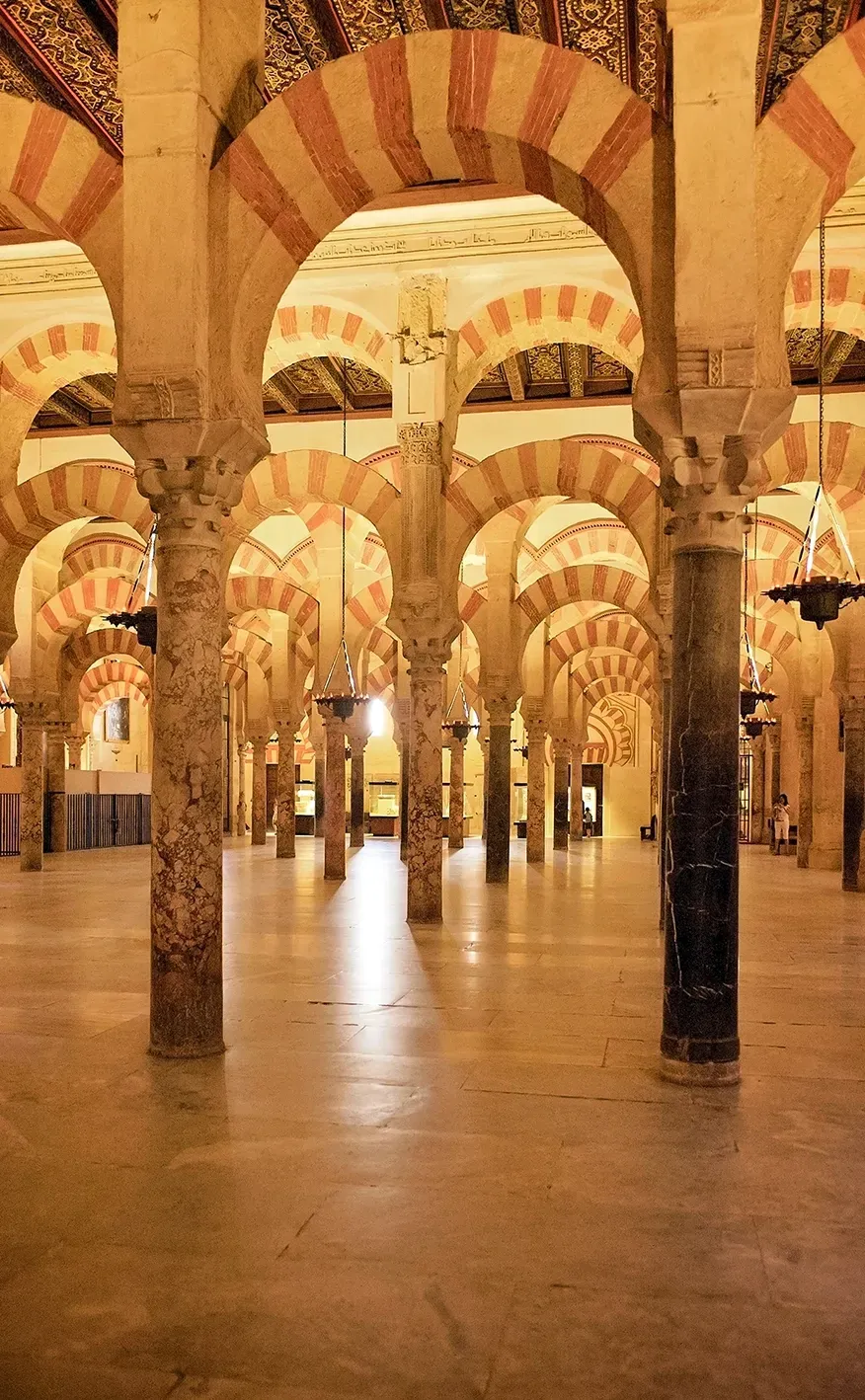 Interior of the Mosque-Cathedral of Córdoba, Spain. Arches with red and white stripes supported by columns.