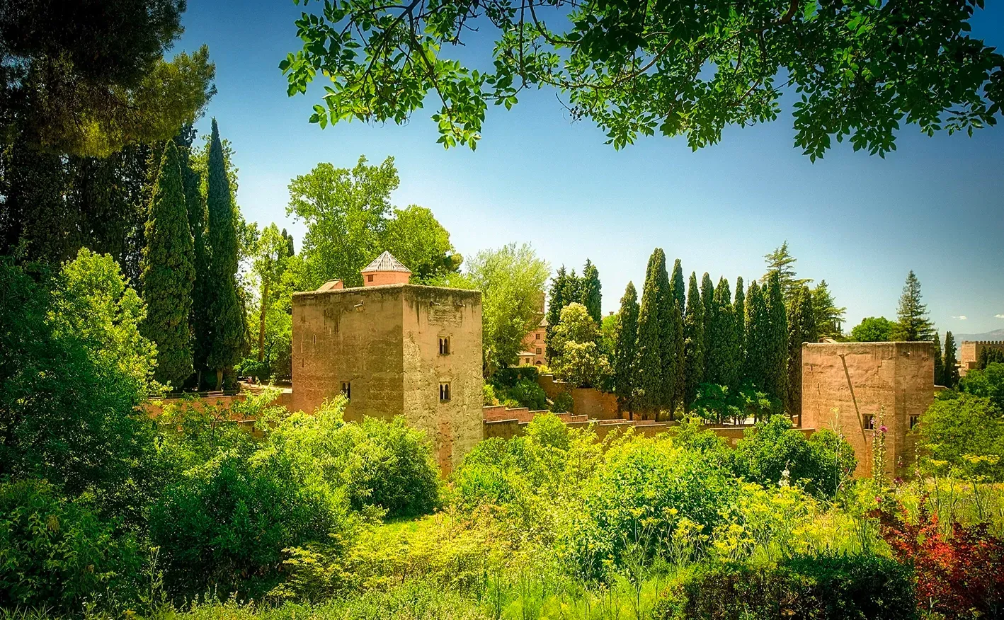 Two stone towers in a lush green garden, under a bright blue sky.