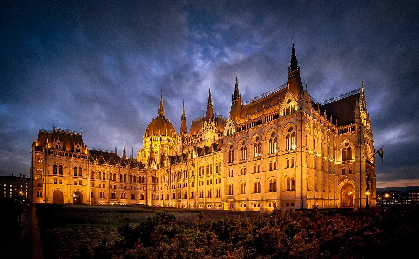 Hungarian Parliament Building illuminated at dusk. Golden lights against dark blue sky.