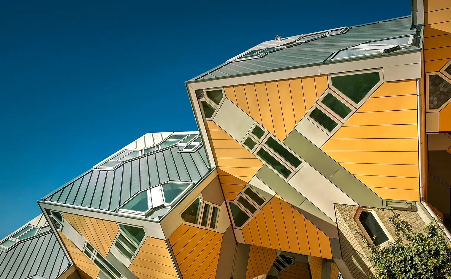 Yellow Cube Houses in Rotterdam against a blue sky, showcasing unique tilted architecture.