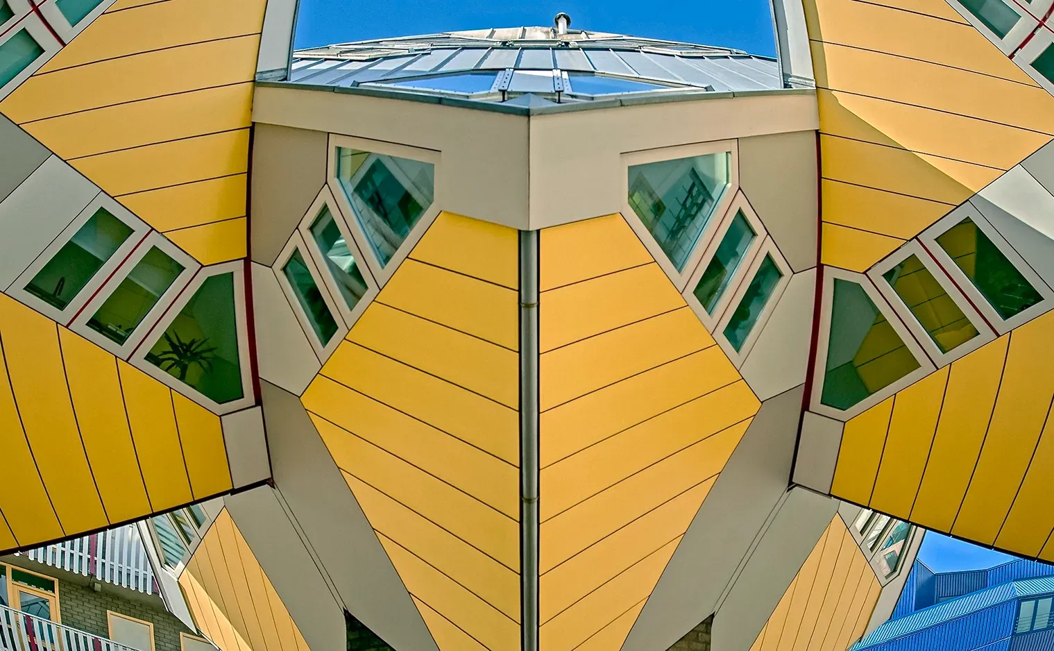 Yellow cube-shaped houses in Rotterdam, Netherlands; angled design with windows against a blue sky.