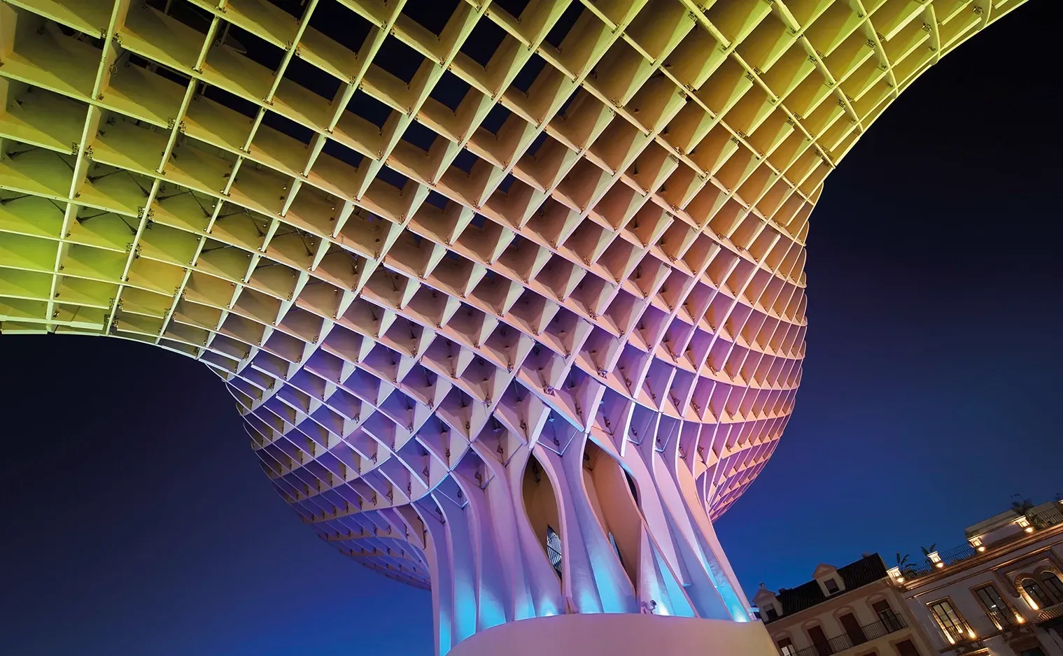 Metropol Parasol in Seville, Spain at night, illuminated with a gradient of colors.