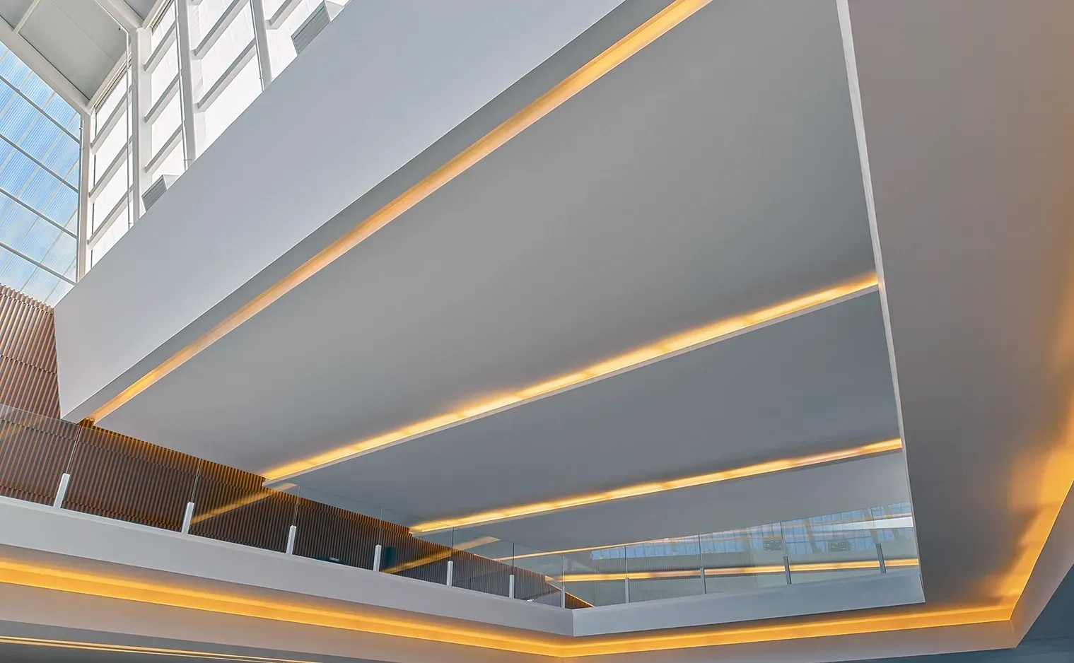 Modern interior with white walls, recessed warm lighting, and glass railings.