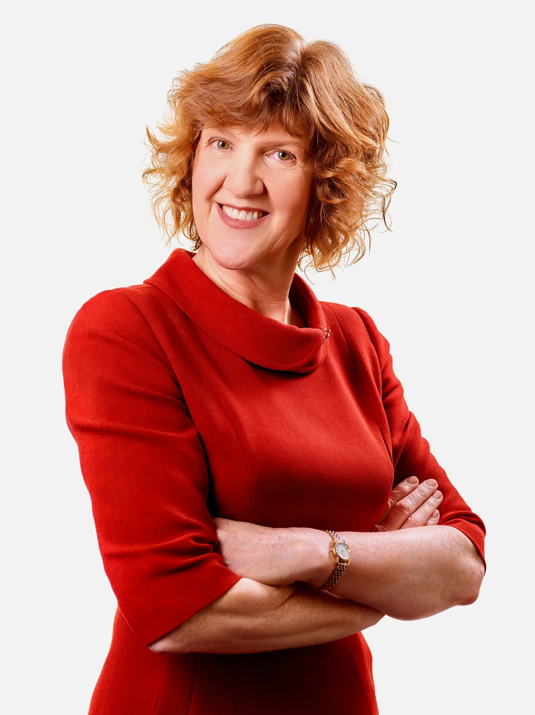 Woman with red hair and a red dress, arms crossed, smiling.