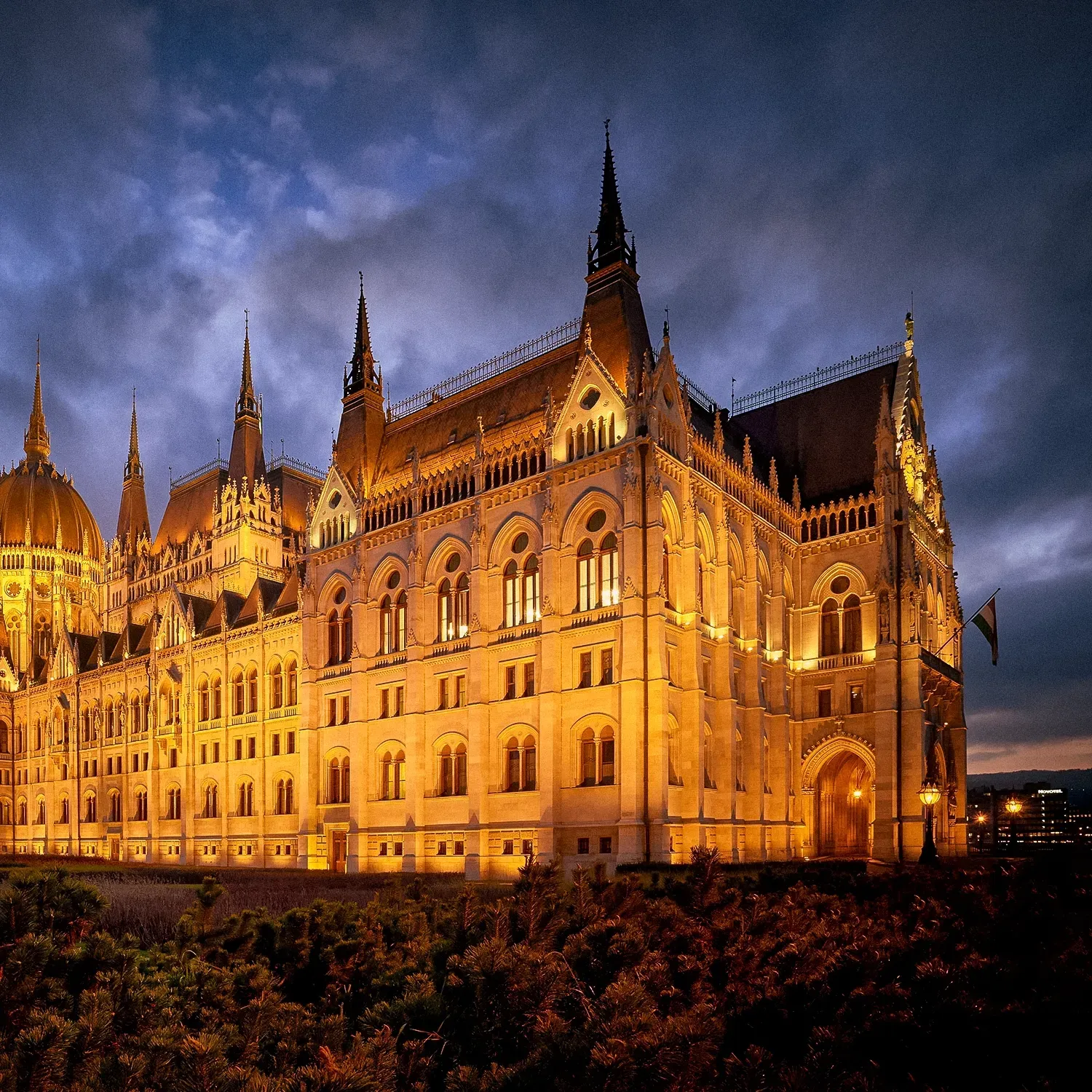 Hungarian Parliament Building illuminated at dusk, featuring ornate architecture and spires.