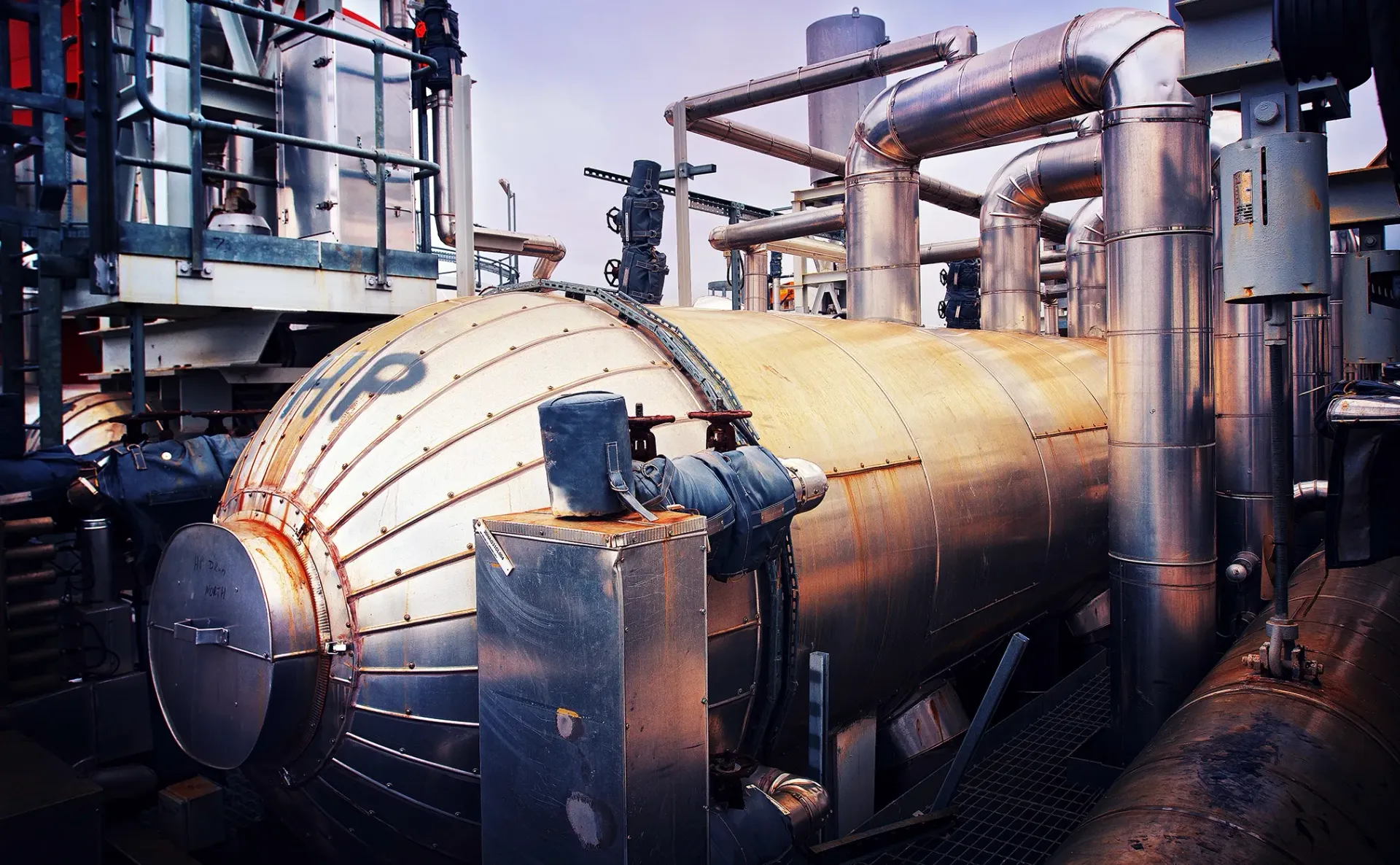 Large industrial metal tank with pipes and equipment.