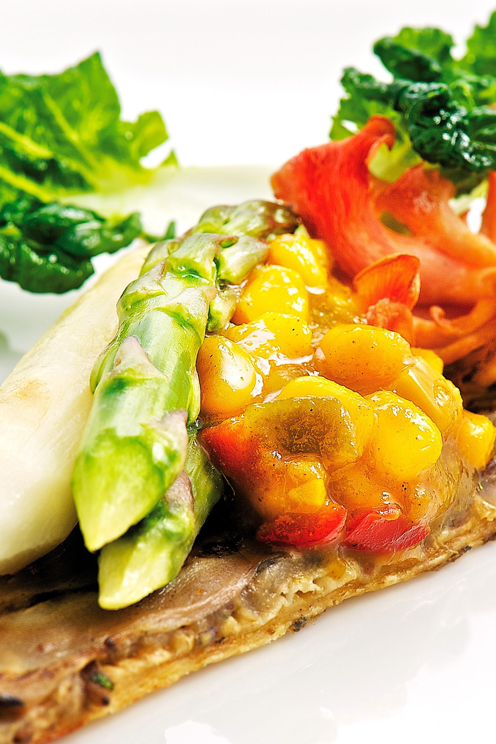 Asparagus and yellow sauce atop a pastry, with lettuce and tomato garnish.