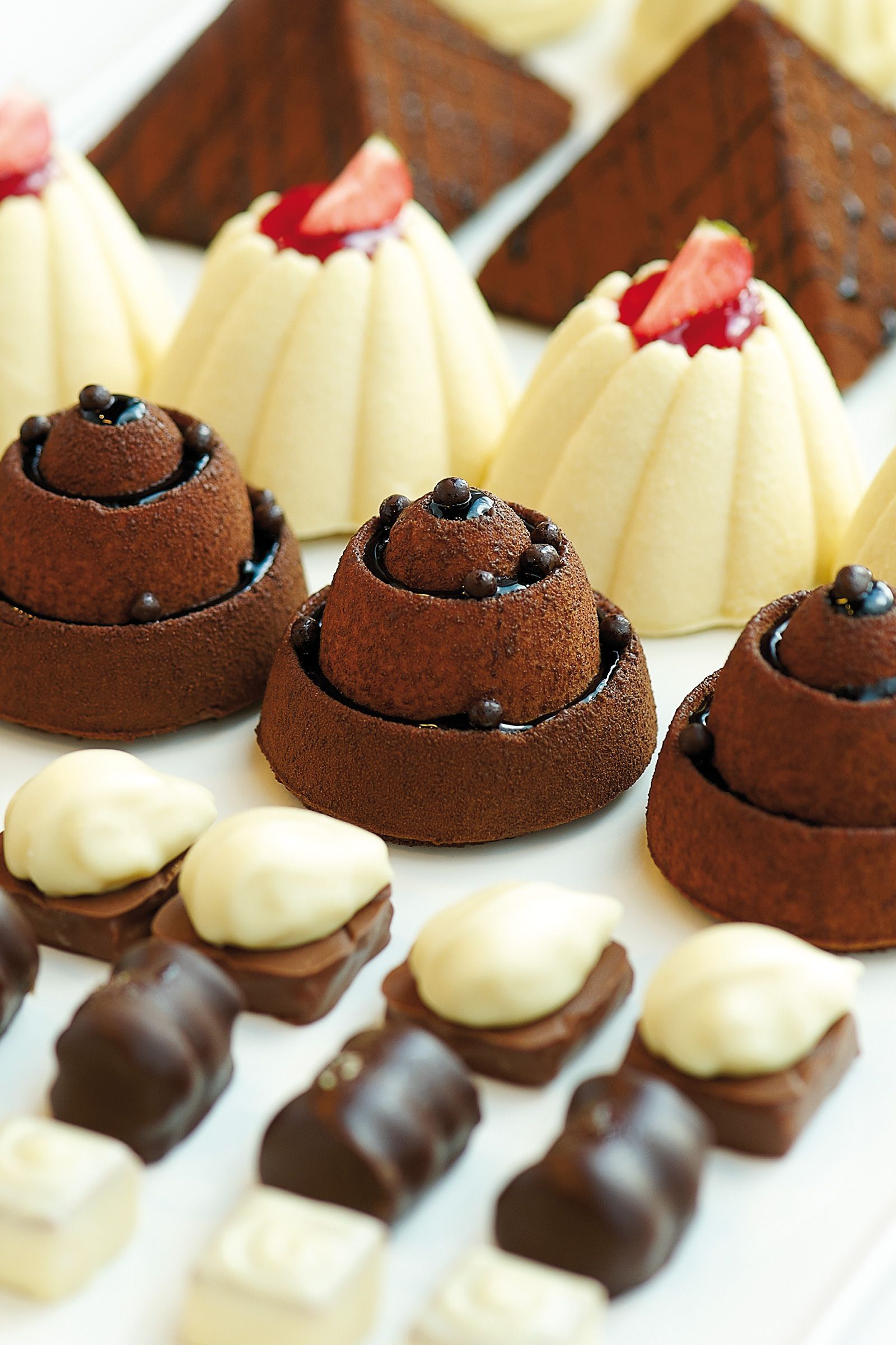 Close-up of assorted chocolates, including white and dark chocolate shapes with strawberry garnish.
