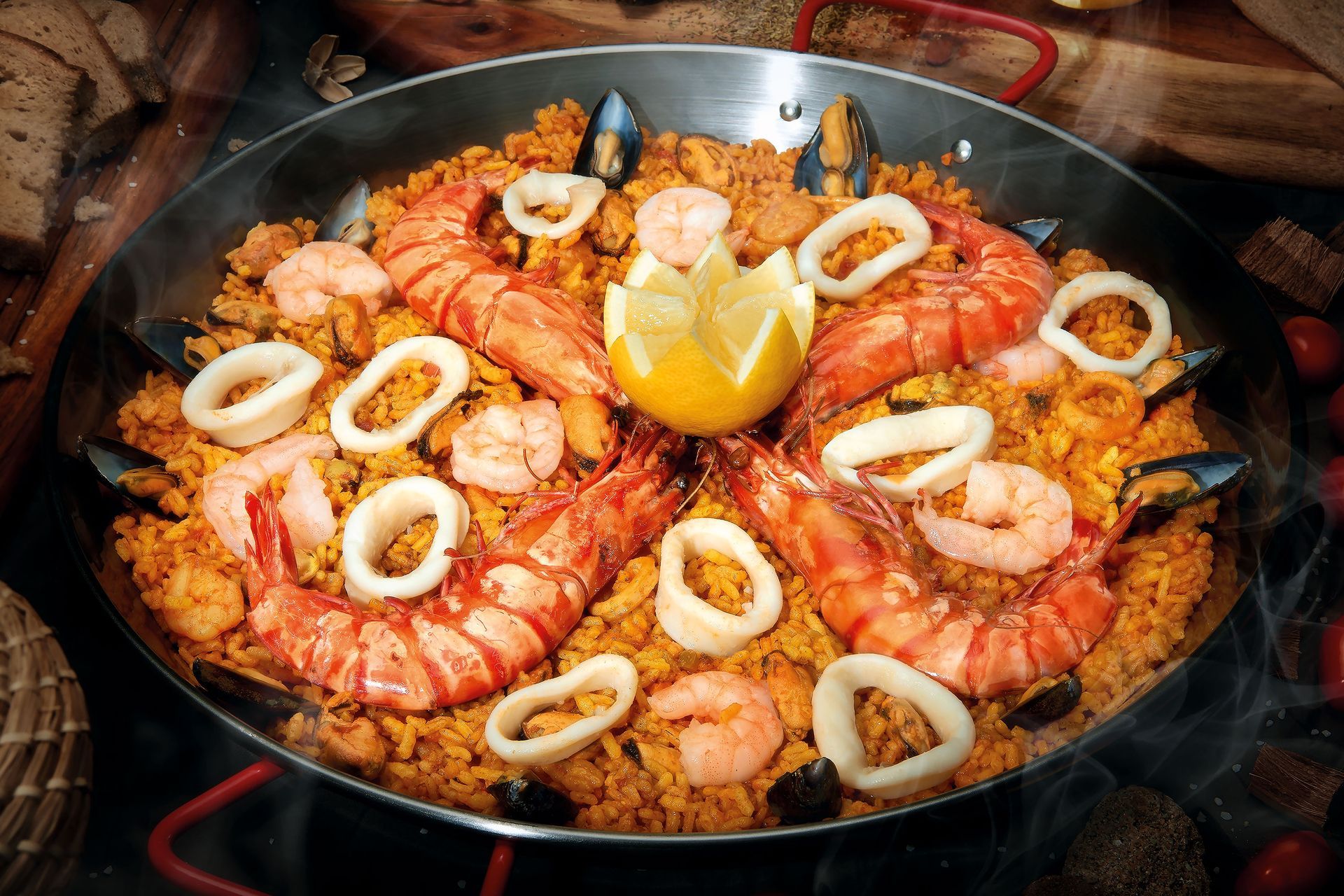 Paella with shrimp, calamari, mussels, and lemon in a large pan.