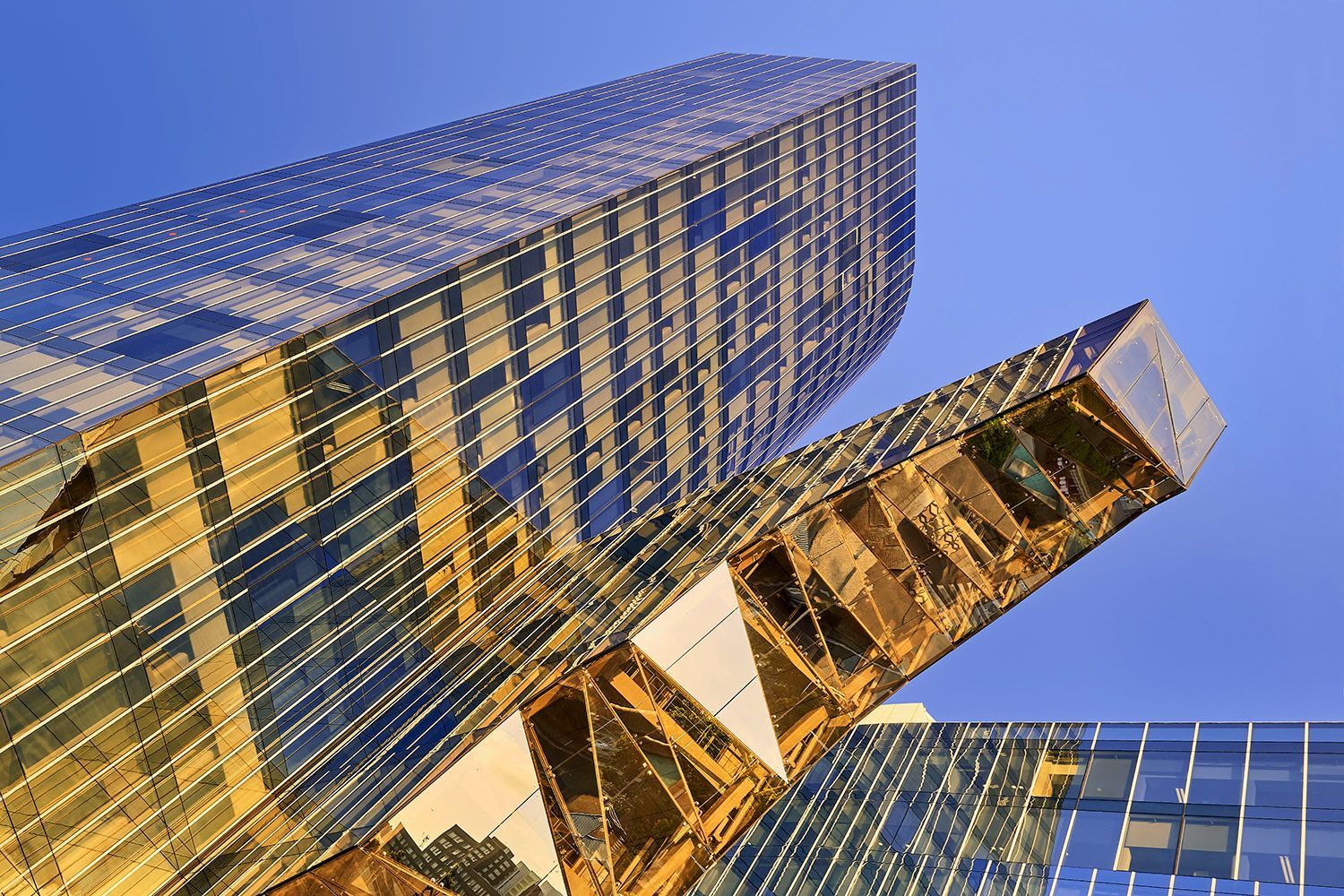 Skyscrapers with gold-toned glass exteriors against a clear blue sky.