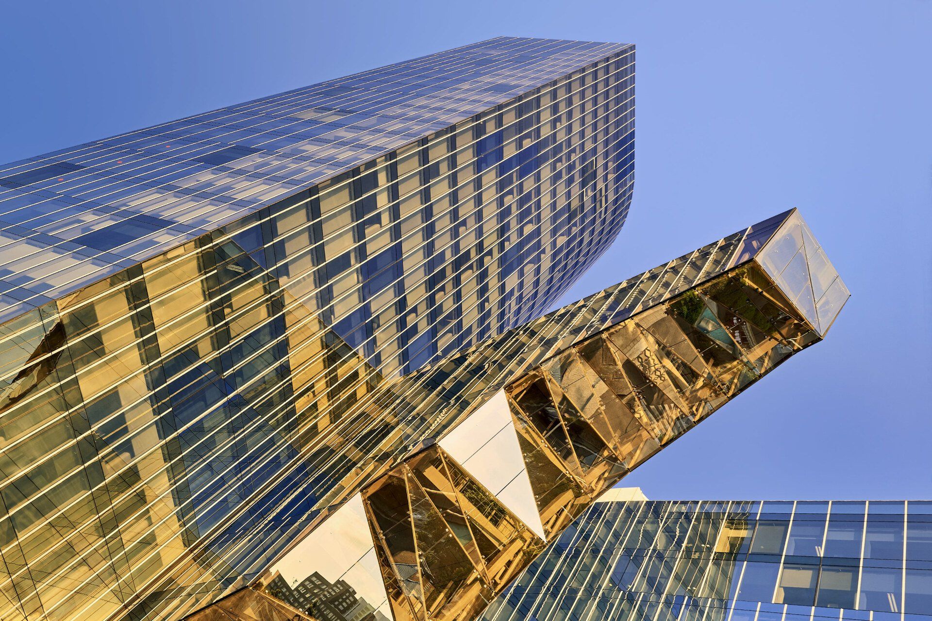 Modern golden glass skyscraper angled against a blue sky.
