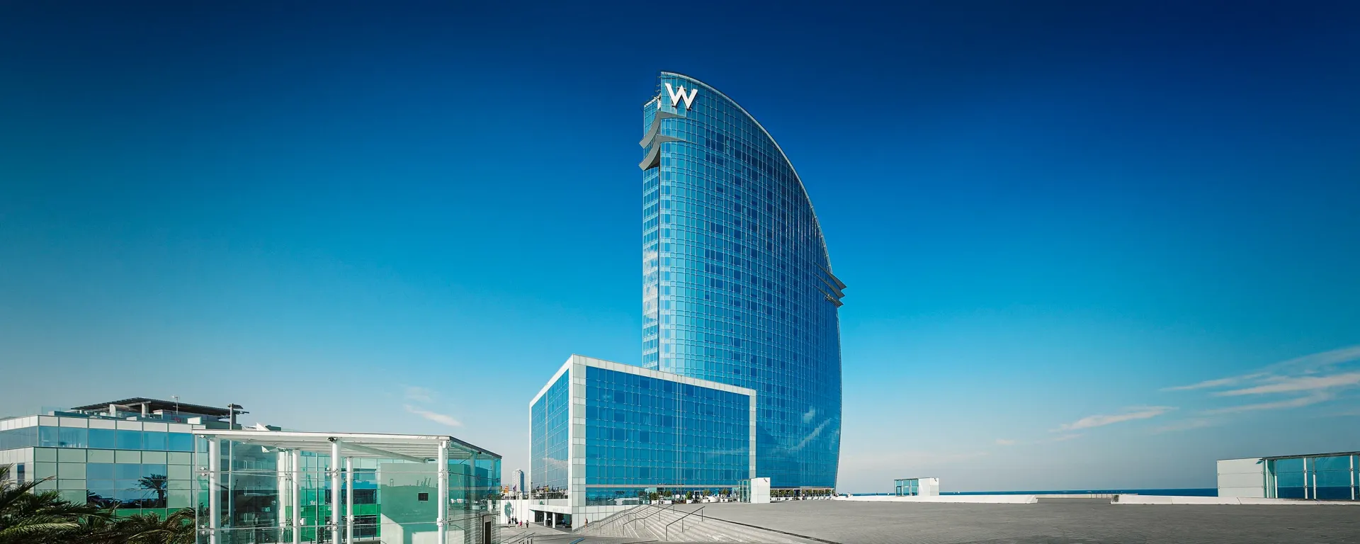 Modern, blue glass hotel building against a clear, blue sky.