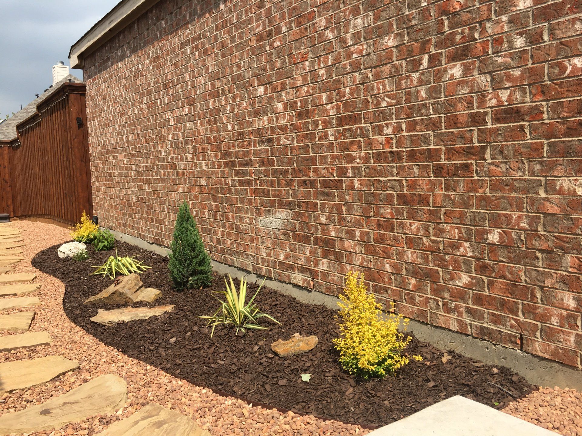 Paved walkway going past a small flower garden