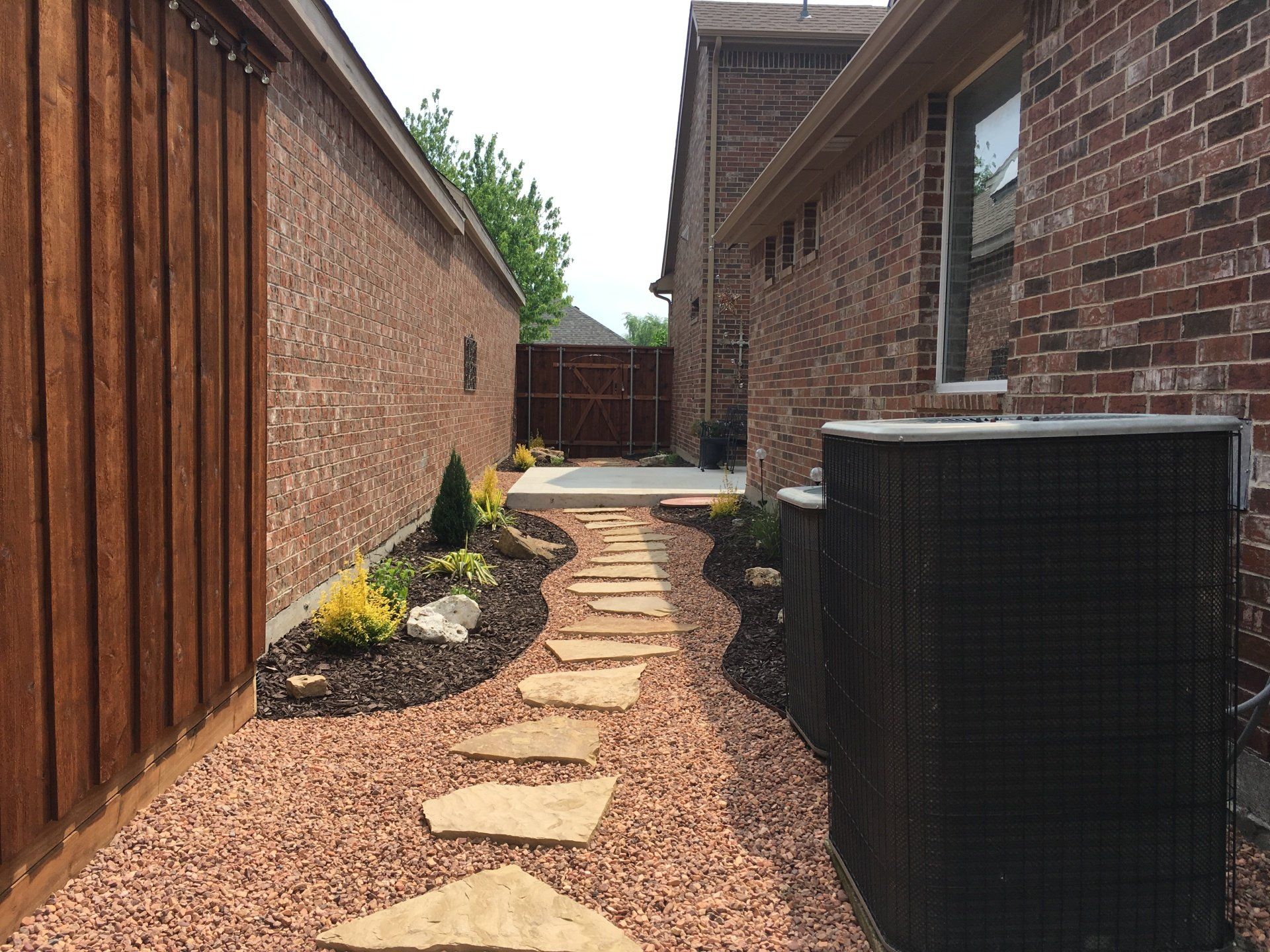 Paved walkway made by Clay's Clipper's going past some AC units