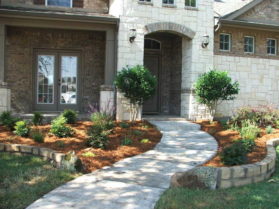 Paved walkway leading into the front door with a garden on either side