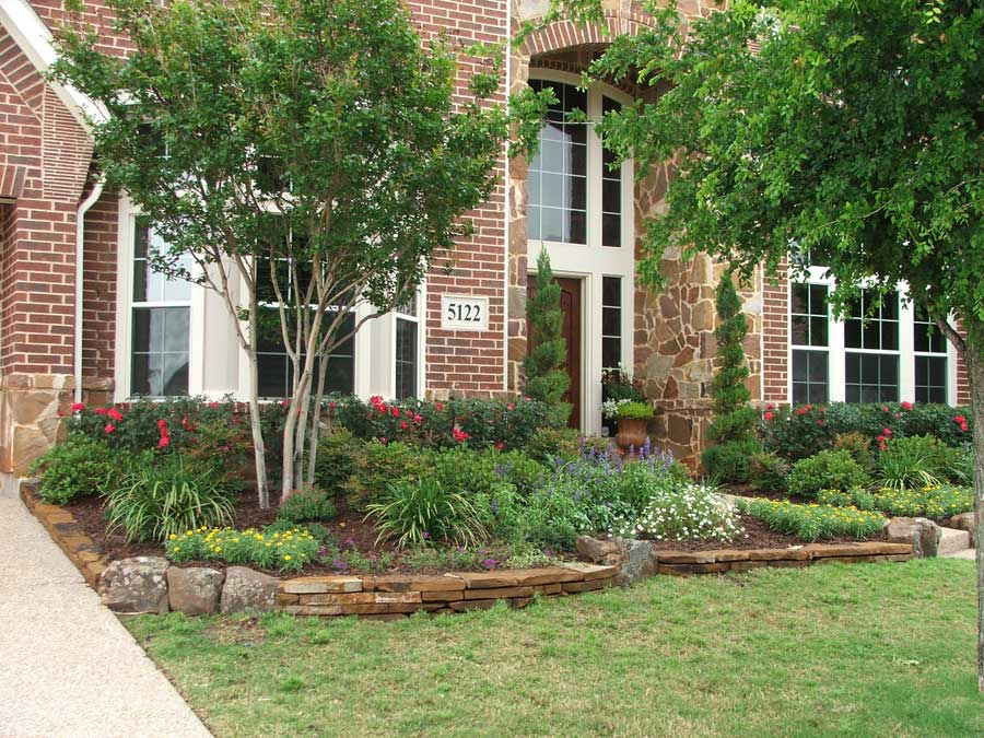 A garden with trees and bushes outside of a window next to a green lawn
