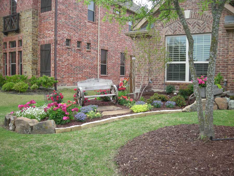 A bench in the middle of a garden amid a landscaped lawn